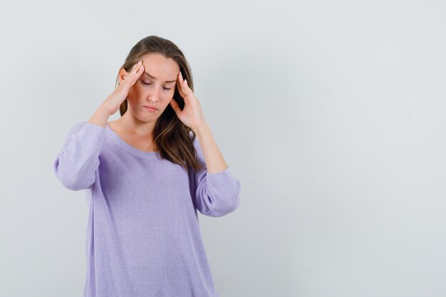 Jonge dame in casual shirt tempels wrijven en vermoeid op zoek