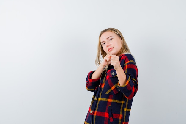 Jonge dame in geruit overhemd die zich in gevechtshouding bevinden en op zoek zelfverzekerd, vooraanzicht.