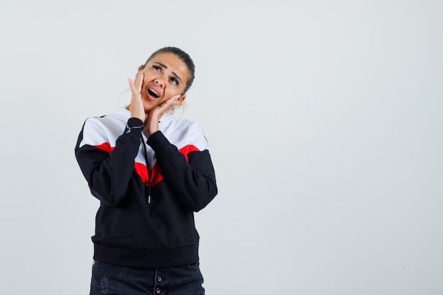 Jonge dame in kleurrijke sweater die iemand belt en gefocust, vooraanzicht kijkt.