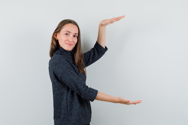 Jonge dame in overhemd die groot grootteteken tonen en zelfverzekerd kijken.