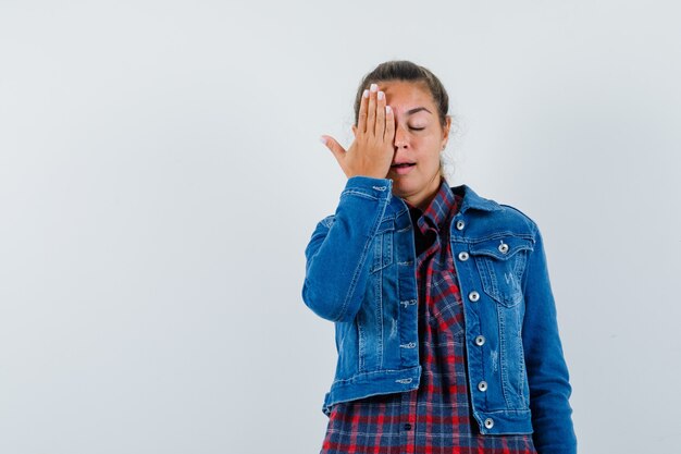 Jonge dame in overhemd, jasje die hand op ogen houdt en dromerig, vooraanzicht kijkt.