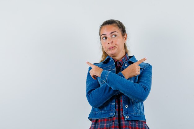 Jonge dame in overhemd, jasje wijst weg en kijkt dromerig, vooraanzicht.