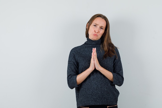 Jonge dame in overhemd namaste gebaar tonen en nederig kijken