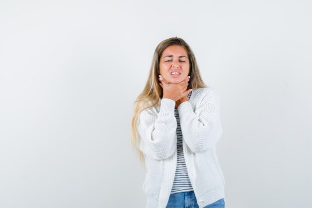 Jonge dame in t-shirt, jasje die aan keelpijn lijdt en ziek kijkt, vooraanzicht.