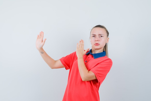 Jonge dame in t-shirt karate hakken gebaar tonen en streng kijken