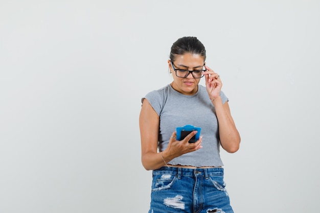 Jonge dame in t-shirt, korte broek kijkt uit over notities op mini klembord