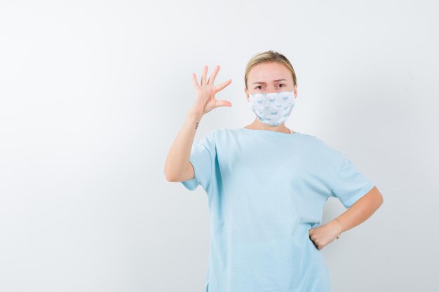 Jonge dame in t-shirt, masker met een klein bordje en ziet er serieus uit