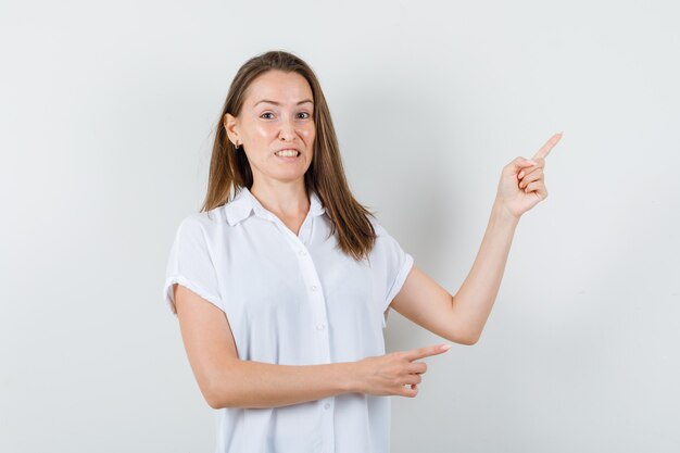 Jonge dame in witte blouse die opzij wijst en verveeld kijkt