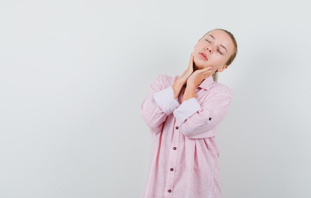 Jonge dame poseren met gesloten ogen in roze shirt en op zoek verleidelijk