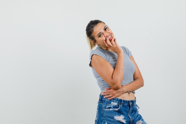 Jonge dame poseren terwijl je in een t-shirt, korte broek en er verleidelijk uitziet