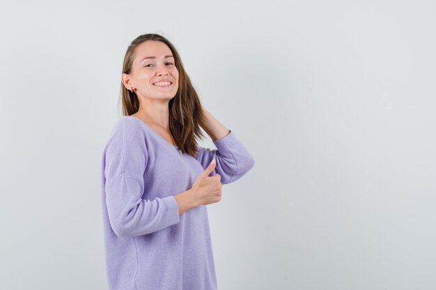 Jonge dame poseren terwijl staande in casual shirt en op zoek gelukkig. vooraanzicht.