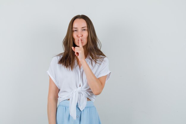 Jonge dame stilte gebaar in blouse, rok tonen en kalm op zoek