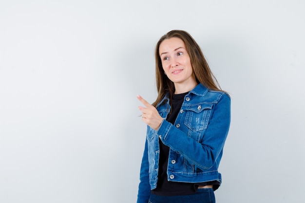 Jonge dame waarschuwing met vinger in blouse, jas en zelfverzekerd, vooraanzicht.