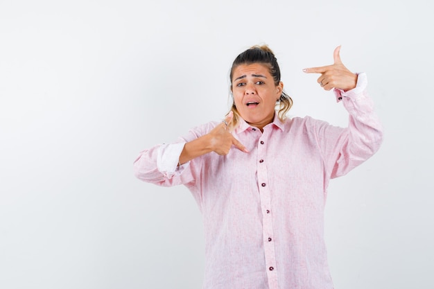 Jonge dame wijzend op zichzelf in roze shirt en angstig op zoek