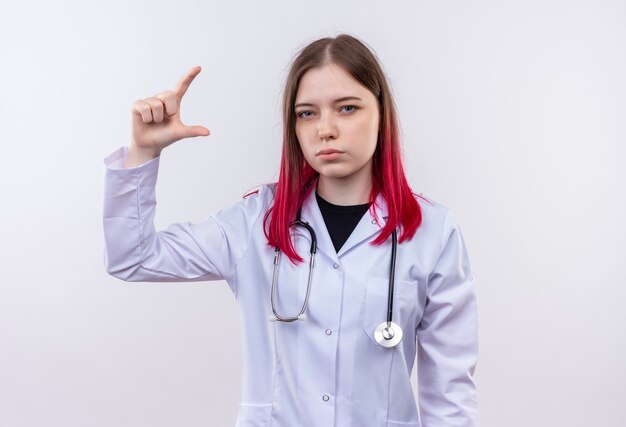 jonge dokter vrouw dragen stethoscoop medische mantel doen alsof iets op geïsoleerde witte muur te houden