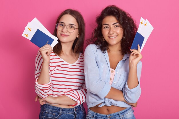 Jonge dolblije vrouwelijke studenten die paspoorten met instapkaartkaartjes houden Premium Foto