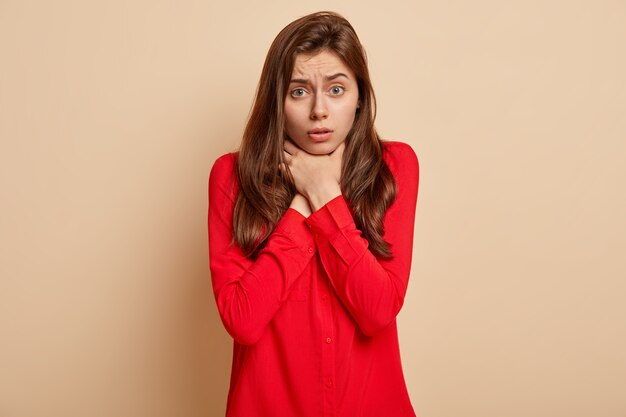 Jonge donkerbruine vrouw die rood overhemd draagt