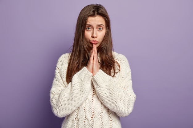 Jonge donkerbruine vrouw die witte sweater draagt