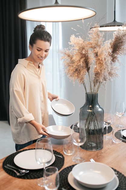 Jonge donkerharige vrouw die de tafel in de keuken bedient