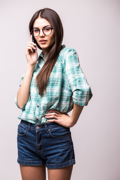 Jonge elegante vrouw praten over de mobiele telefoon tegen wit