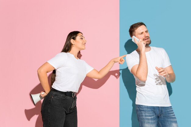 Jonge emotionele man en vrouw op roze en blauwe muur