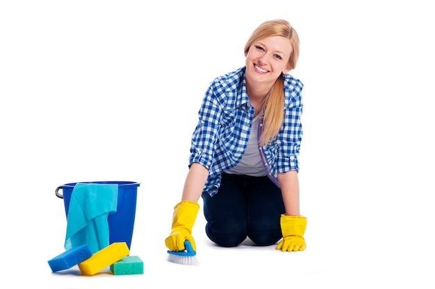 Jonge en glimlachende vrouw die een vloer schoonmaken