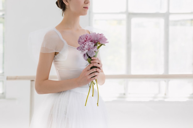 Jonge en ongelooflijk mooie ballerina poseert en danst in een witte studio