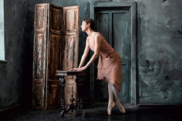 Jonge en ongelooflijk mooie ballerina poseert en danst in een zwarte studio