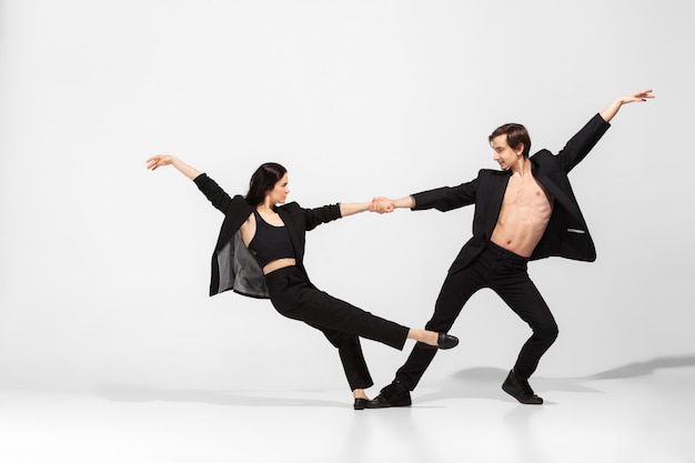Jonge en sierlijke balletdansers in minimale zwarte stijl op wit wordt geïsoleerd