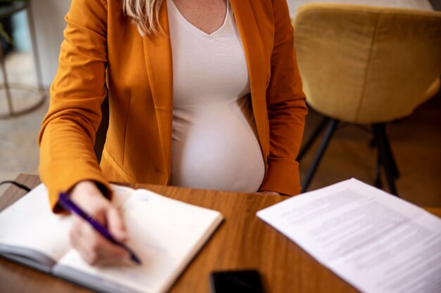 Jonge en zwangere vrouw aan het werk