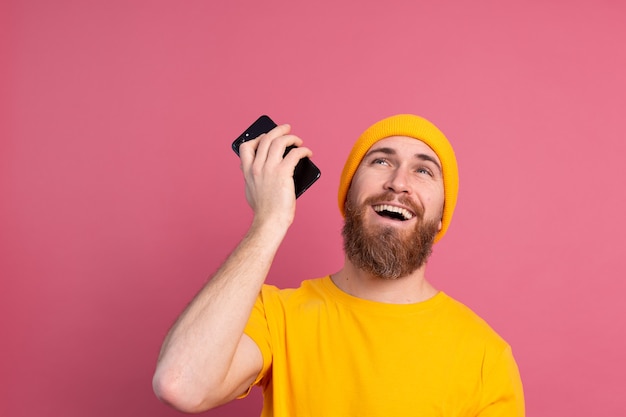 Jonge europese knappe man glimlachend gelukkig luisteren audiobericht met smartphone op roze