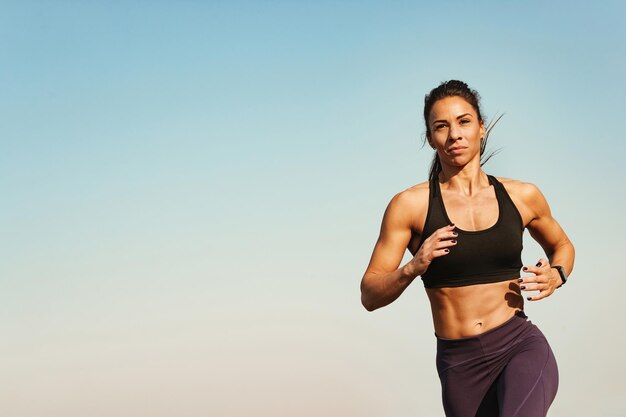 Jonge fitnessinstructeur voelt zich gemotiveerd tijdens het rennen tegen de lucht Ruimte kopiëren