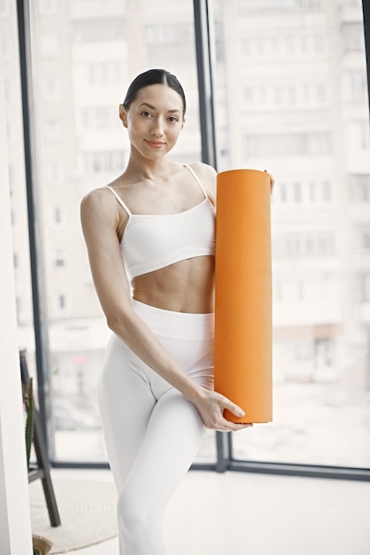 Gratis foto jonge fitnessvrouw klaar voor training met oranje yogamat