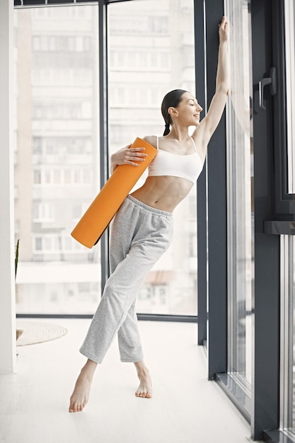 Jonge fitnessvrouw klaar voor training met oranje yogamat
