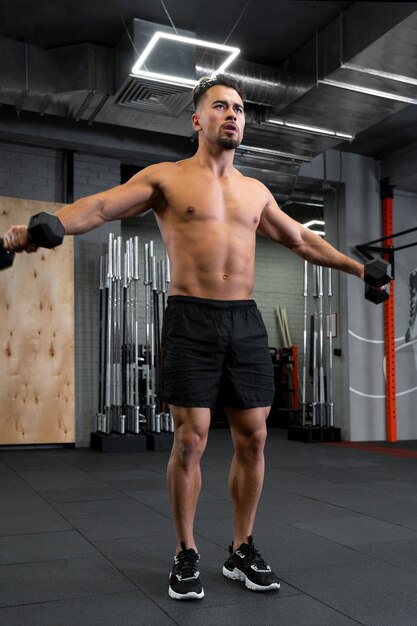 Jonge fitte man aan het trainen met halters in de sportschool