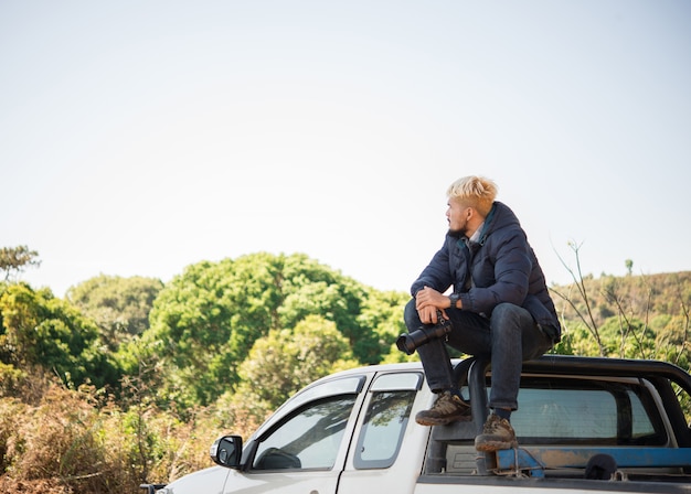 Jonge fotograaf zittend op zijn pick-up truck fotograferen in de berg.