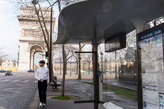 Jonge franse man wacht op het station op de bus en drinkt koffie