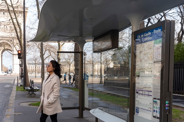 Gratis foto jonge franse vrouw wacht op het station op de bus