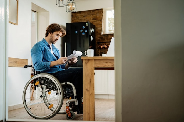 Jonge freelance werknemer die door papierwerk gaat terwijl hij thuis werkt