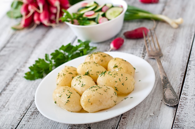 Jonge gekookte aardappelen met boter en dille op een witte plaat