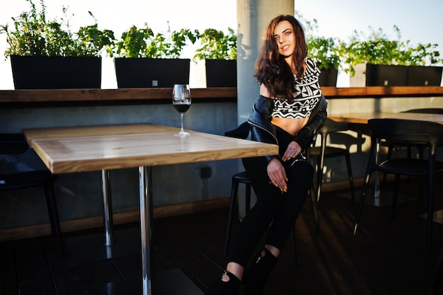 Jonge gekrulde vrouw die van haar wijn geniet in een bar