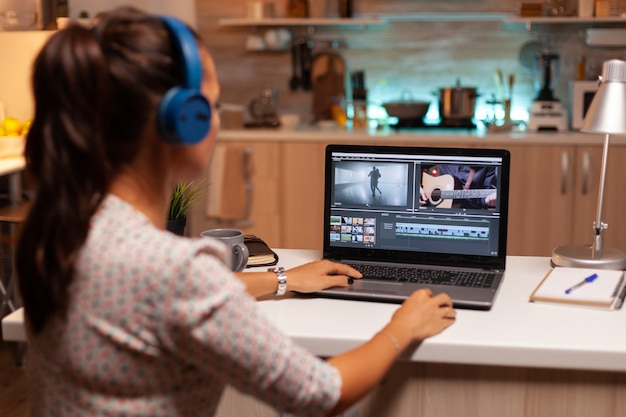 Jonge geluidstechnicus bezig met videobeelden tijdens postproductie. Contentmaker thuis bezig met filmmontage met moderne software voor 's avonds laat bewerken.