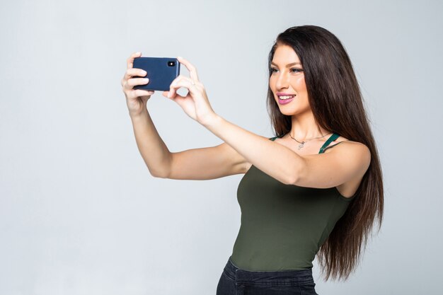 Jonge gelukkig aantrekkelijke vrouw in jurk maakt foto's met behulp van haar mobiele telefoon, schieten