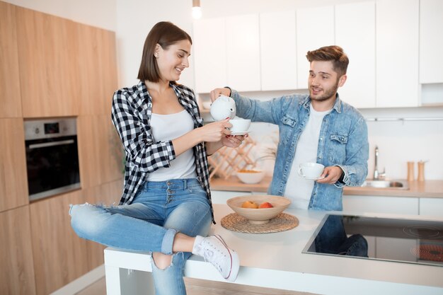 Jonge gelukkig man en vrouw in keuken, ontbijt, paar samen in de ochtend, glimlachen, met thee