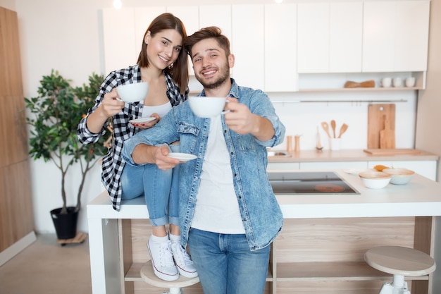 Jonge gelukkig man en vrouw in keuken, ontbijt, paar samen in de ochtend, glimlachen, met thee