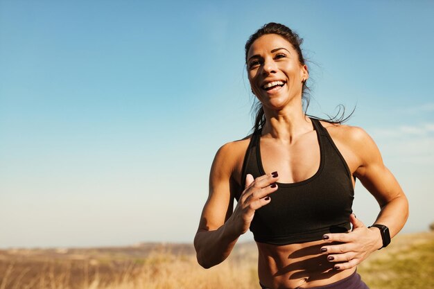 Jonge gelukkige atletische vrouw die plezier heeft tijdens het joggen in de natuur Ruimte kopiëren