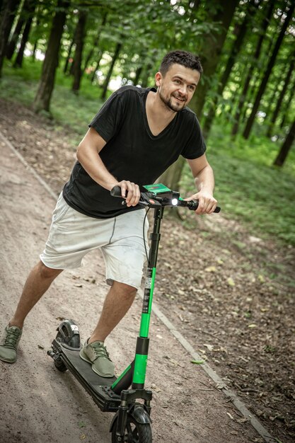 Jonge gelukkige man rijdt op een elektrische scooter, ecologisch transportconcept.