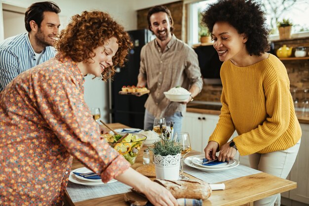 Jonge gelukkige mensen genieten terwijl ze de eettafel bereiden voor de lunch thuis Focus ligt op Afro-Amerikaanse vrouw