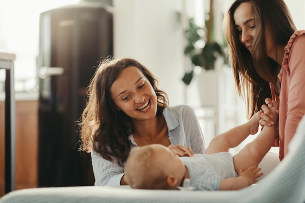 Jonge gelukkige moeders die plezier hebben tijdens het spelen met een baby thuis