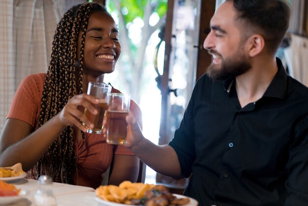 Jonge gelukkige paar genieten van een maaltijd samen terwijl ze een date hebben in een restaurant.